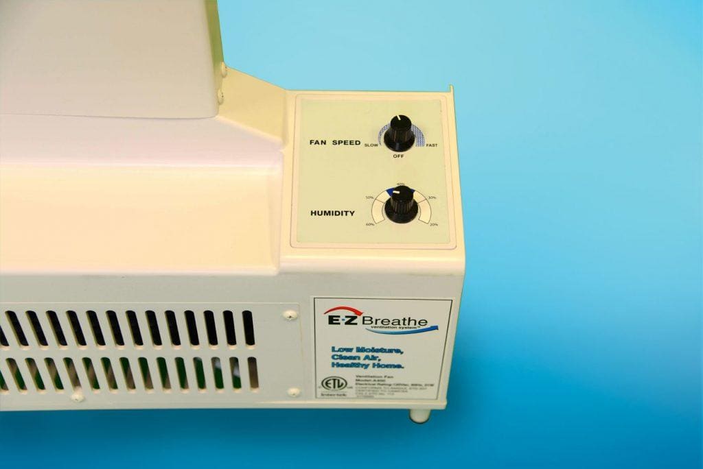 Close-up of an air purifier control panel with two knobs labeled "Fan Speed" and "Humidity." The device has vents and a label reading "EZ Breathe (Taller Height), Basement Model A-400 – Standard chute – for walls up to 10′" and "Low Moisture, Clean Air, Healthy Home.