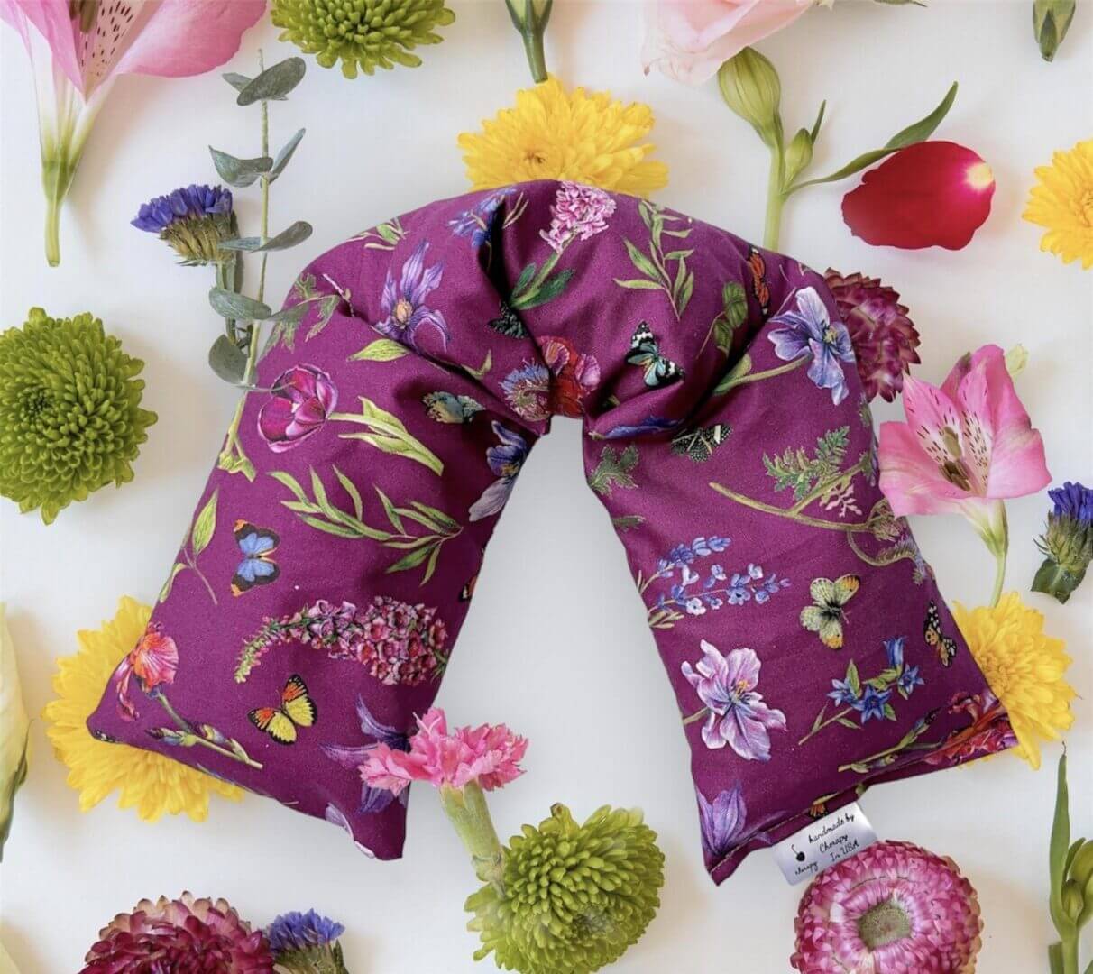 A CHERAPY Wrap Pillow 100 Percent (REGULAR) Cotton – in the Spring Flower Butterfly Design is surrounded by various colorful flowers on a white background.